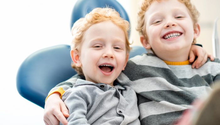 Portrait of a happy young brothers sitting on the dental chair at the dental office